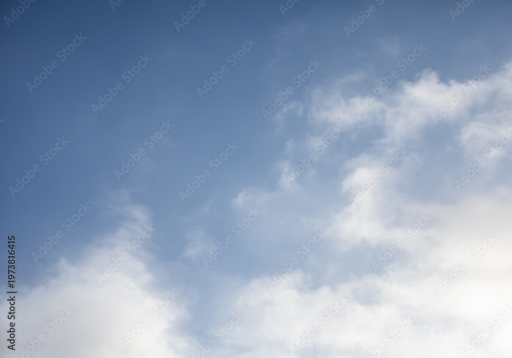 Fototapeta premium Clear blue sky with white clouds scattered across the horizon, creating a serene and tranquil atmosphere in the daytime
