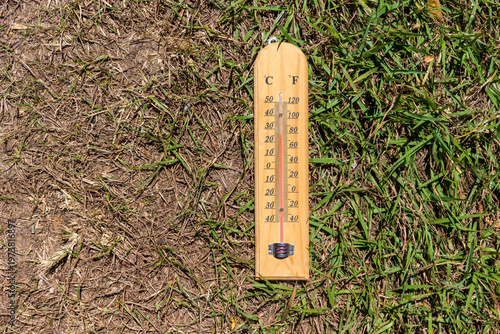 Thermometer on grass showing temperature outdoors in summer