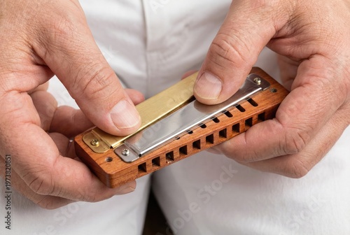 Artisan hands carefully assembling metal reed plates onto wooden comb of diatonic harmonica