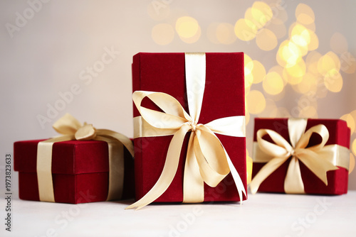 Red gift boxes on white table, closeup. Bokeh effect