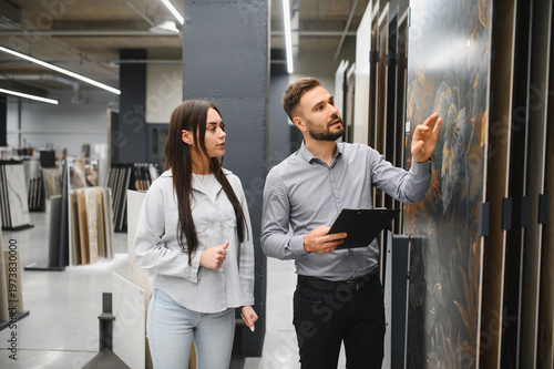 Seller assisting female customer choosing large tiles