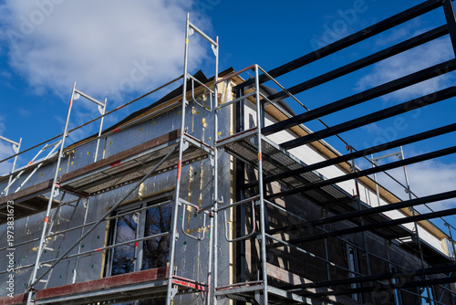 Fotografía Scaffolding and steel roof beams above insulated building facade during renovati