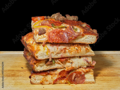 Stack of frozen deep dish pizza slices with pepperoni and sausage