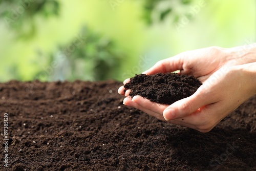 Woman with fresh soil on blurred background, closeup