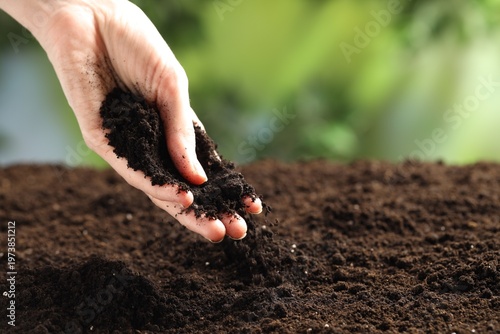 Woman with fresh soil on blurred background, closeup