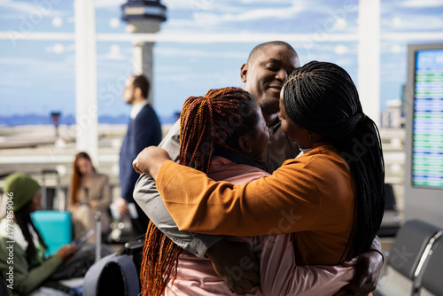 Foto Emotional scene of African American parents hugging daughter in airport terminal, saying bittersweet goodbye before departure flight