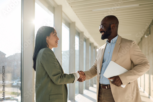 Business colleagues shaking hands after successful meeting in office.