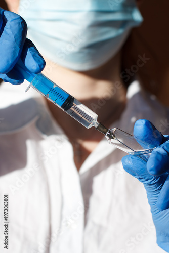 A medical worker draws medicine from an ampoule using a syringe. Medicines