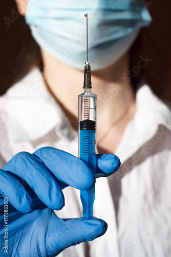 Syringe with an injection drug in the hands of a medical worker. Doctor in a medical mask and gloves