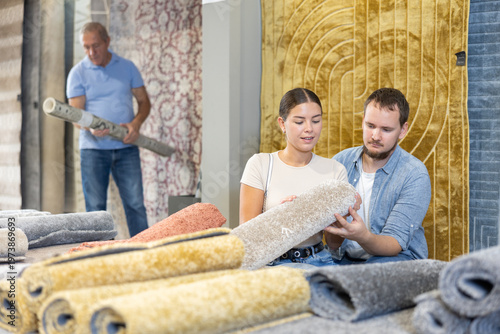 Photography On territory of exhibition hall, husband and wife inspect carpets, choose material and color of product