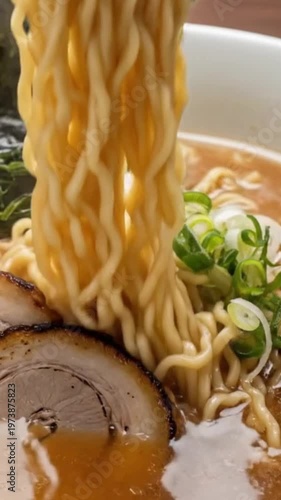 Close-up of delicious ramen noodles being lifted with chopsticks, showcasing toppings