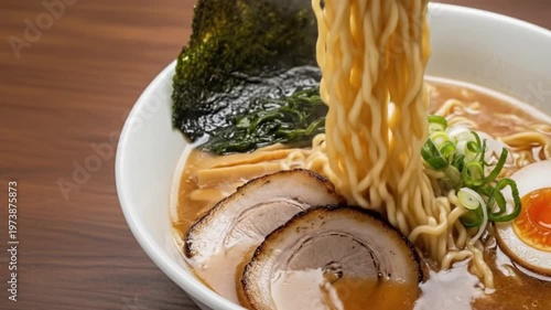 Close-up of delicious ramen being lifted with chopsticks, showcasing tender pork and broth