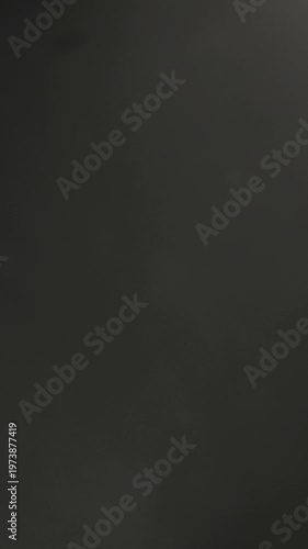 Metal scissors cutting green thread on dark background