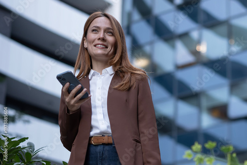 Confident businesswoman holding phone looking forward in urban setting