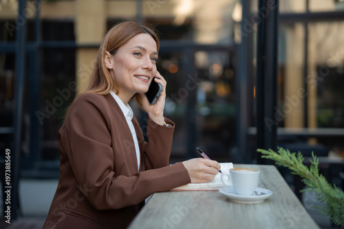 Professional woman smiling, making phone call, writing notes