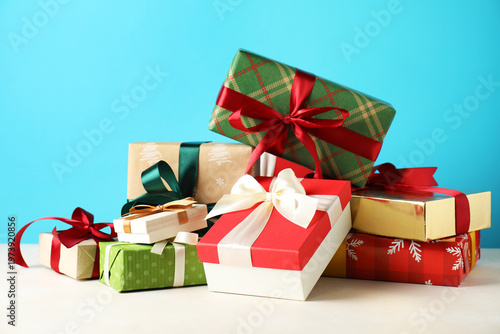 Pile of many gift boxes on light table against blue background, closeup. Merry Christmas and Happy New Year