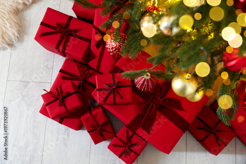Many gift boxes under Christmas tree indoors, top view