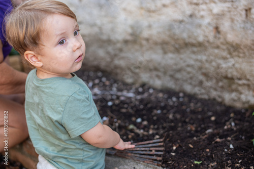 Child using a hand rake to plant