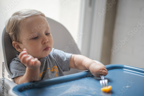 Left-handed baby learning how to use fork