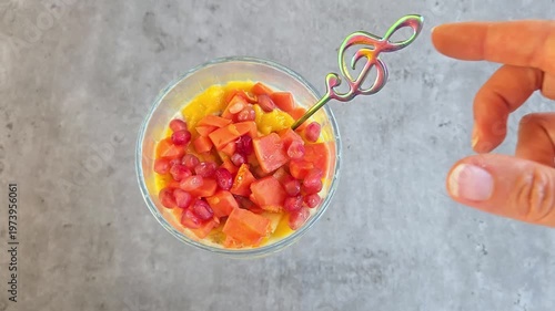 Chia pudding with multi fruit mango, papaya and pomegranate in glass jar. Vegan breakfast concept. Top view on grey marble table