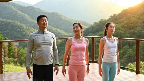 Asian family doing yoga exercises on mountain terrace at sunset
