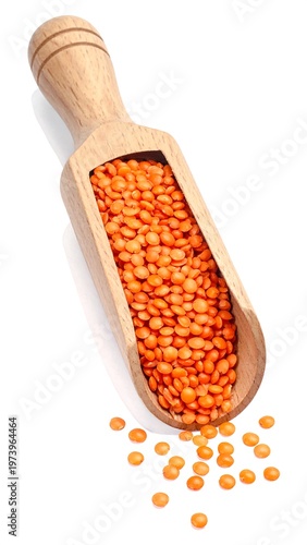 A wooden scoop filled with red lentils on a white background