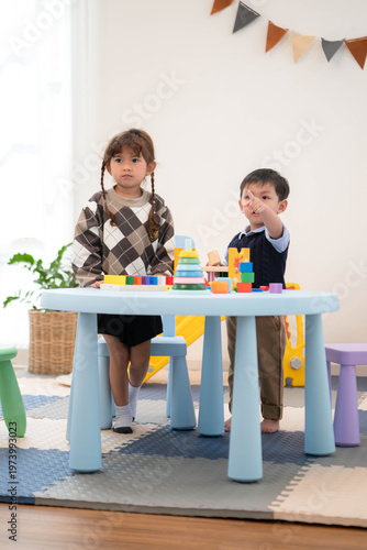 Little boy and girl playing with toys together in the playroom