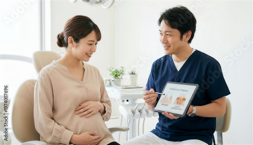 タブレットを使って妊婦の患者に歯周病の予防や治療について説明する男性歯科医