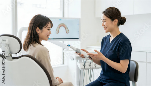 歯科医院で口腔内スキャナーを持って笑顔で女性患者に説明する歯科医師
