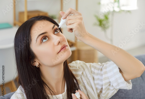 Fotografi Woman using medical eyes drops suffering from dry eyes syndrome or curing ophtha
