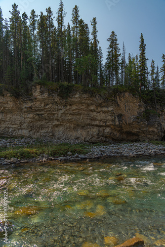 Scenic summer landscape of Elbow Falls in Kananaskis Country, Alberta, Canada. Beautiful waterfall cascading over rocky cliffs into the Elbow River with evergreen pine forest and blue sky Canada
