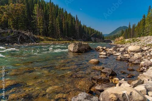 Scenic summer landscape of Elbow Falls in Kananaskis Country, Alberta, Canada. Beautiful waterfall cascading over rocky cliffs into the Elbow River with evergreen pine forest and blue sky Canada