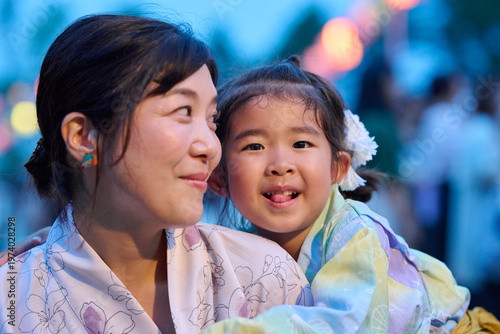 母に抱かれてカメラ目線の女の子と微笑む母親