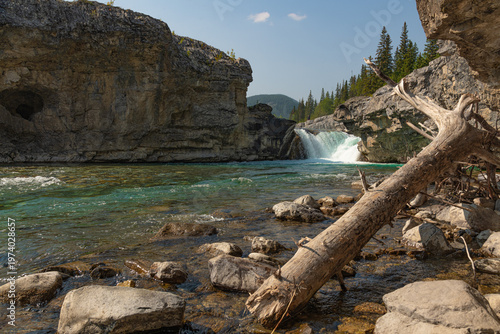 Scenic summer landscape of Elbow Falls in Kananaskis Country, Alberta, Canada. Beautiful waterfall cascading over rocky cliffs into the Elbow River with evergreen pine forest and blue sky Canada