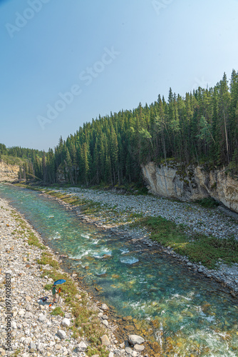 Scenic summer landscape of Elbow Falls in Kananaskis Country, Alberta, Canada. Beautiful waterfall cascading over rocky cliffs into the Elbow River with evergreen pine forest and blue sky Canada