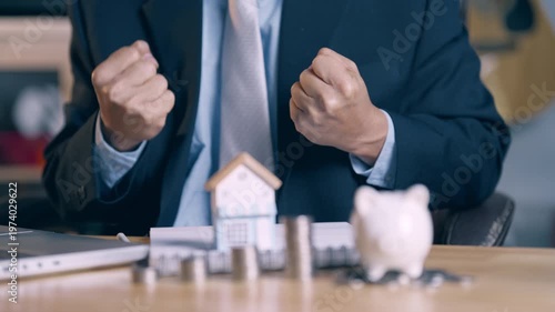 Successful businessman celebrating home loan approval with clenched fists and happy gesture.