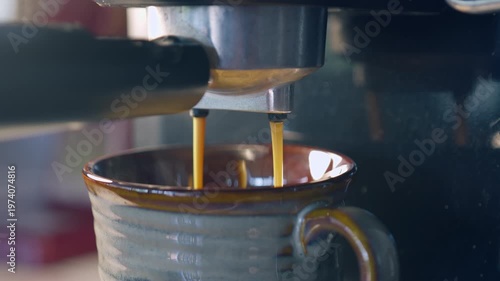 Slow motion espresso coffee pouring from machine into ceramic cup for fresh morning breakfast.