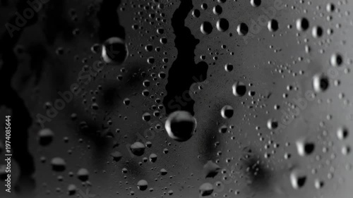 Close-up of water droplets on a dark, reflective surface, creating a textured and abstract background.