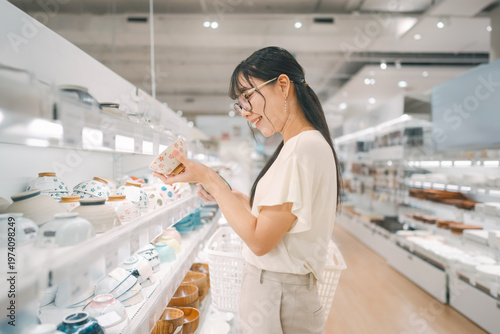 Foto Smiling asian woman shopping choosing plate product for home at indoors japan st