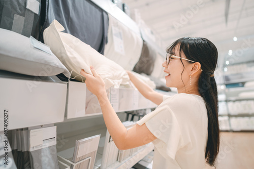 Vászonkép Smiling asian woman shopping choosing bed pillow product for home at indoors jap