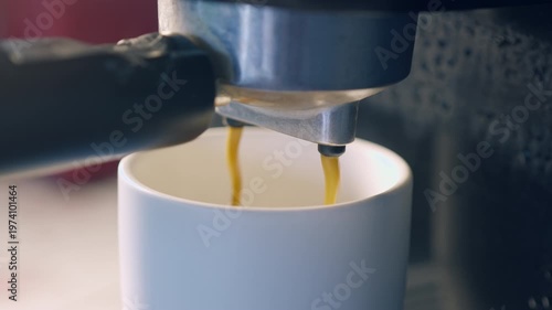 Slow motion espresso coffee pouring from machine into ceramic cup for fresh morning breakfast.
