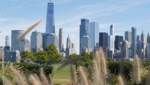 New York City Manhattan Downtown Financial District skyline, World Trade Center tower from New Jersey Liberty state park, United States. Green grass lawn, flowers and skyscraper buildings cityscape.