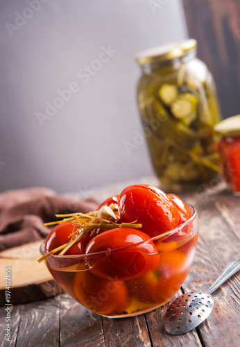 Assortie Jars of Marinated vegetables picles tomato on a wooden background