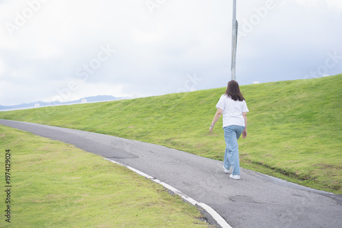 Relax and wellness concept with woman walk on road in garden and mountain background at chiangmai thailand in raining season
