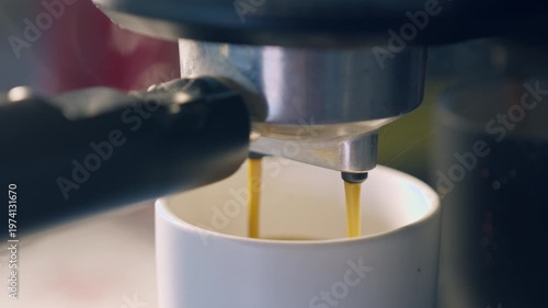 Slow motion espresso coffee pouring from machine into ceramic cup for fresh morning breakfast.