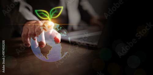 A businessman touching a digital glowing Earth globe with a growing green leaf sprout. Conceptual imagery for global environmental sustainability, corporate social responsibility, and green business.