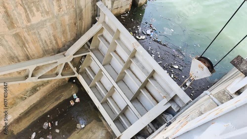 Hydraulic dam and gate mechanism feature heavy steel structure for water control. Massive metal frame connects to cables for vertical movement. This hydraulic dam part operates through gate mechanism.