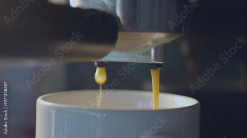 Slow motion espresso coffee pouring from machine into ceramic cup for fresh morning breakfast.