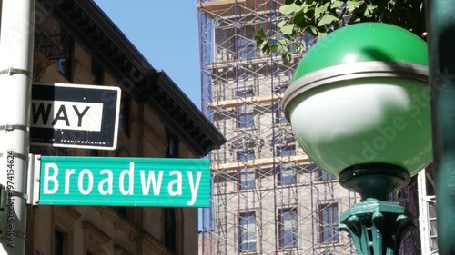 New York City Broadway street sign in Manhattan Midtown, United States. Urban road sign, traffic sign. Building architecture in Flatiron district. Subway metro entrance green globe lamp.