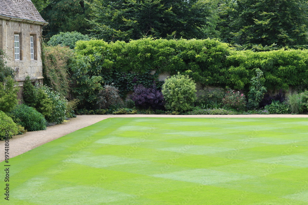Obraz premium Neatly mown lawn surrounded by a garden path and flower beds